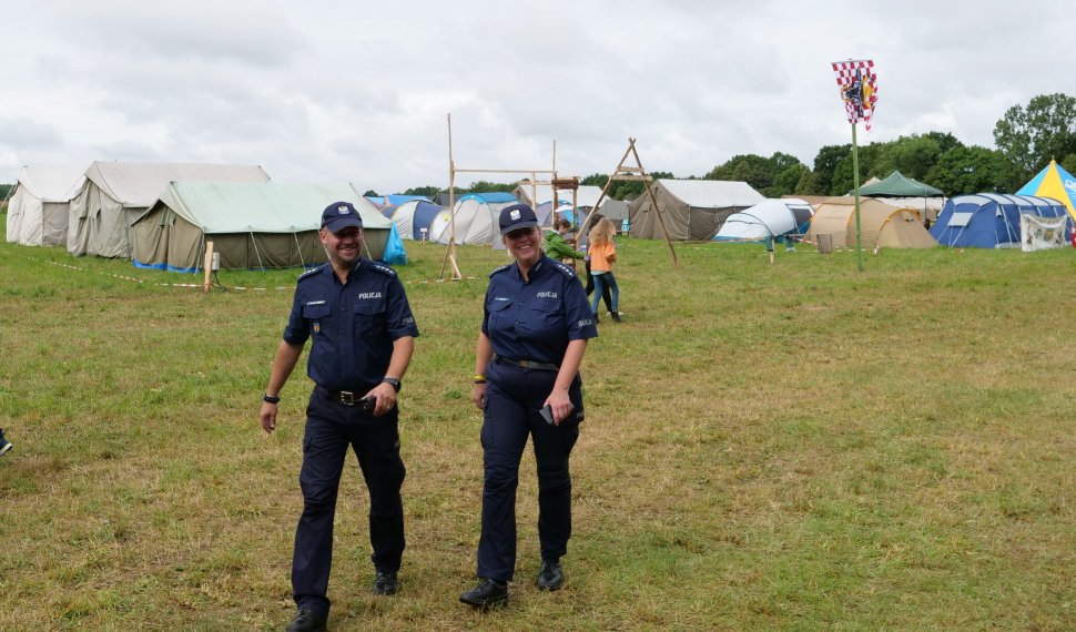 Policjantka i policjant idą przez pole namiotowe na zlocie gruwaldzkim