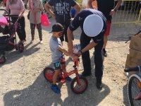 Policjant zakłada dziecku oświetlenie na rower.