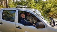 Policjant razem ze Strażnikiem Leśnym patrolują wspólnie teren leśny pojazdem terenowym.
