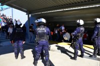 Policjanci stoją przy wejściu podziemnym dworca PKP, którym przechodzą kibicie piłkarscy.