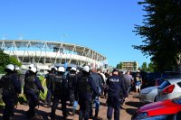 Policjanci prowadzą kibiców na stadion piłkarski.