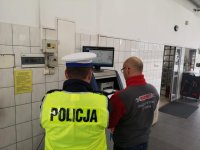 Policjant i diagnosta obserwują wyniki sprawdzenia pojazdu na monitorze komputera.