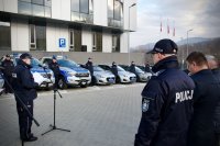 Komendant Policji w Bielsku-Białej przemawia, w tle nowe radiowozy.