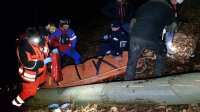 Policjanci i ratownicy GOPR udzielają pomocy poszkodowanemu, umieszczonemu na noszach.