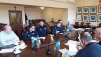 Czterech policjantów siedzi przy stole podczas obrad gminnej komisji bezpieczeństwa.
