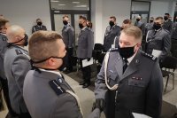 Komendant Miejski Policji w Bielsku-Białej wręcza policjantowi akt mianowania. W tle policjanci stoją  na baczność.