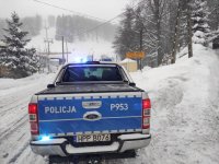 Terenowy policyjny radiowóz stoi na zaśnieżonej drodze.