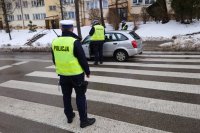 Policjanci z drogówki wykonują czynności służbowe na przejściu dla pieszych. Na pasach stoi osobowy samochód marki Mazda.