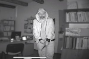 Czarno-biały wizerunek sprawcy kradzieży z włamaniem zarejestrowany przez monitoring biura